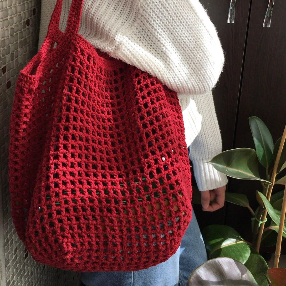 Person holding a red woven bag against a neutral background